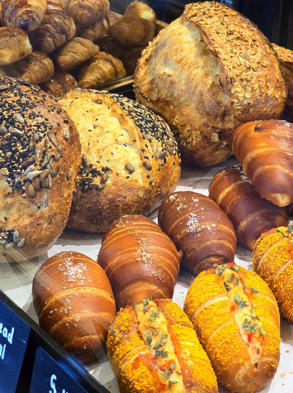 Seeded sourdough loaves and pretzel croissants in the bread case