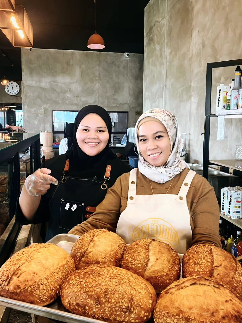 Two bakers holding a tray of fresh sourdough loaves